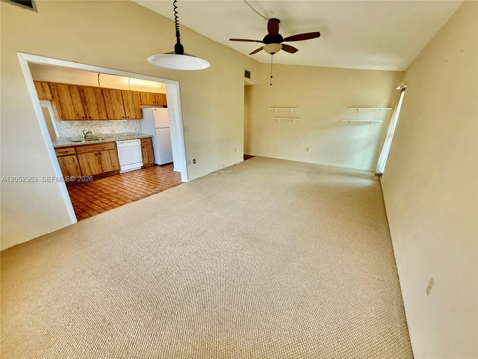 A carpeted living room opens into a kitchen with wood cabinets and tile flooring — 3620 Farragut St, Hollywood FL 33021, HOLLYWOOD, FL