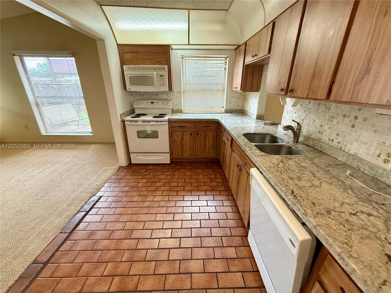 A kitchen features wood cabinets, granite countertops, a white appliance suite, and terracotta tile flooring — 3620 Farragut St, Hollywood FL 33021, HOLLYWOOD, FL