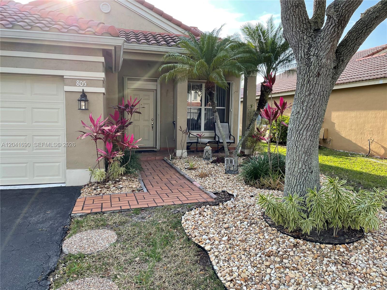 A single-story house exterior features a brick walkway, rock landscaping, and a large tree — 805 Falling Water Rd, Weston FL 33326, WESTON, FL