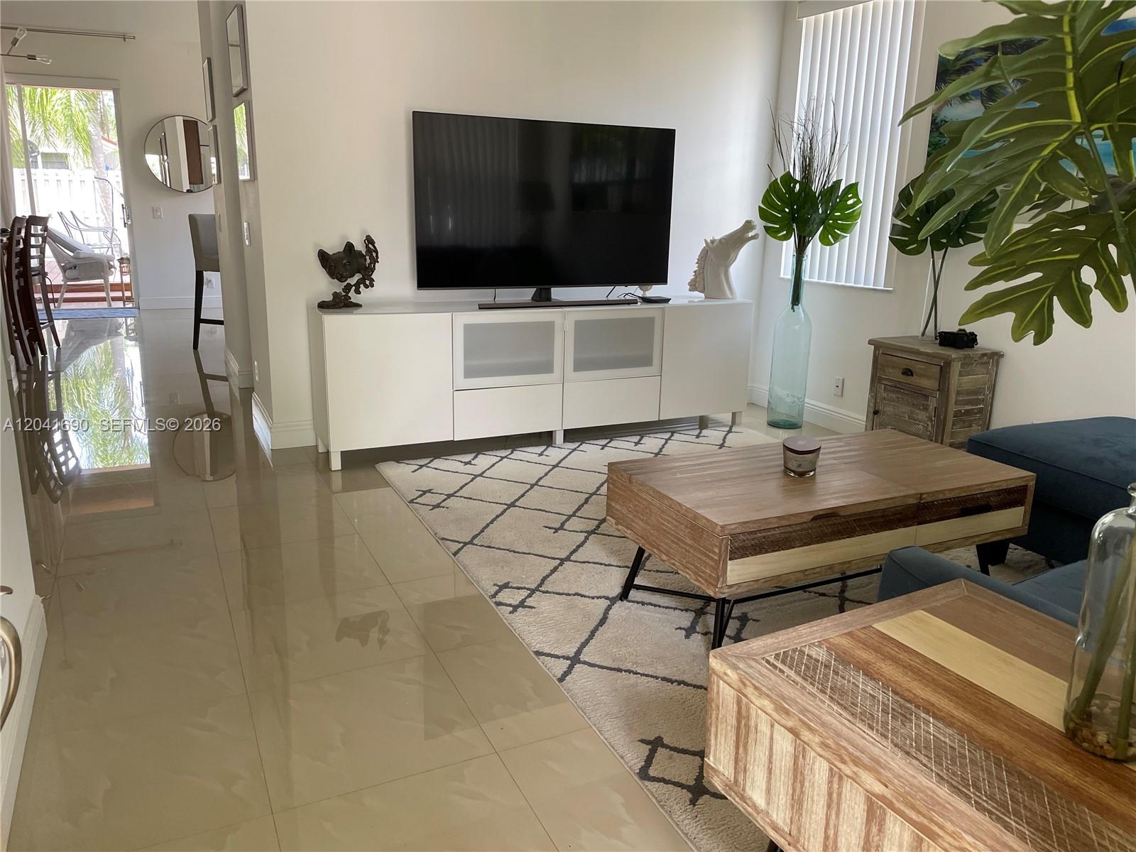 A living room features a white media console, a patterned rug, and wooden coffee tables — 805 Falling Water Rd, Weston FL 33326, WESTON, FL