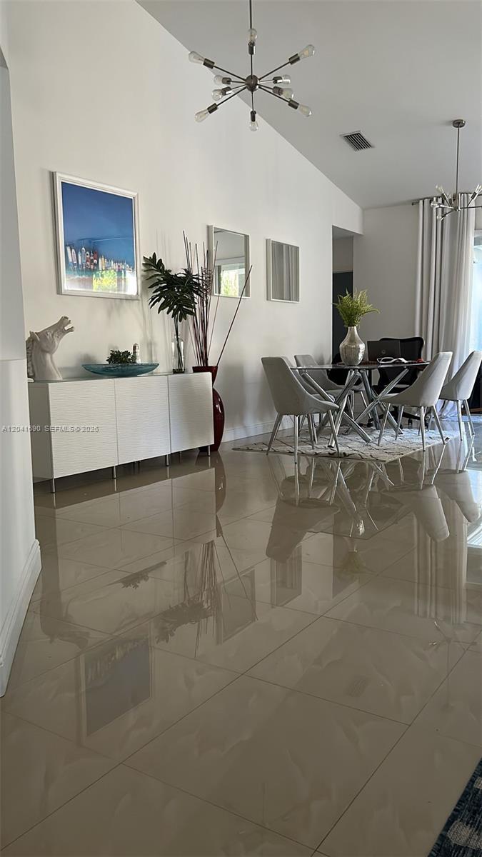 A dining area features a glass table with six chairs, a sideboard, and tile flooring — 805 Falling Water Rd, Weston FL 33326, WESTON, FL