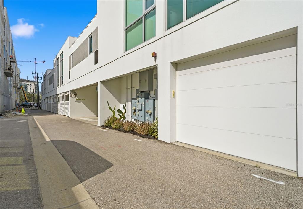 An exterior view of a modern white townhouse with a garage and utility equipment — 1350 5TH STREET UNIT 402, SARASOTA, FL