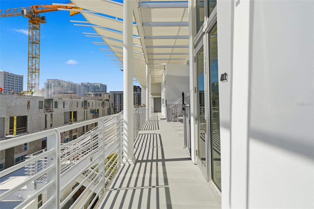 A modern balcony with white railings overlooks a construction site with a large yellow crane — 1350 5TH STREET UNIT 402, SARASOTA, FL