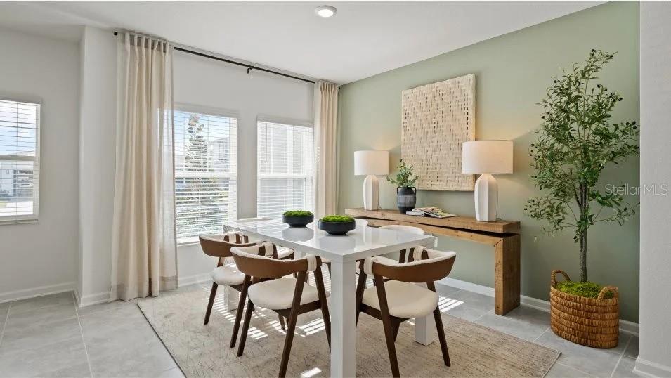 A dining room features a white table, modern chairs, a wood console, and sage walls — 11309 RISING SUN STREET, ORLANDO, FL