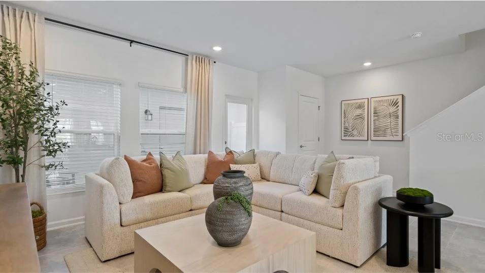 A living room features a light-colored sectional sofa, a wooden coffee table, and two windows — 11309 RISING SUN STREET, ORLANDO, FL