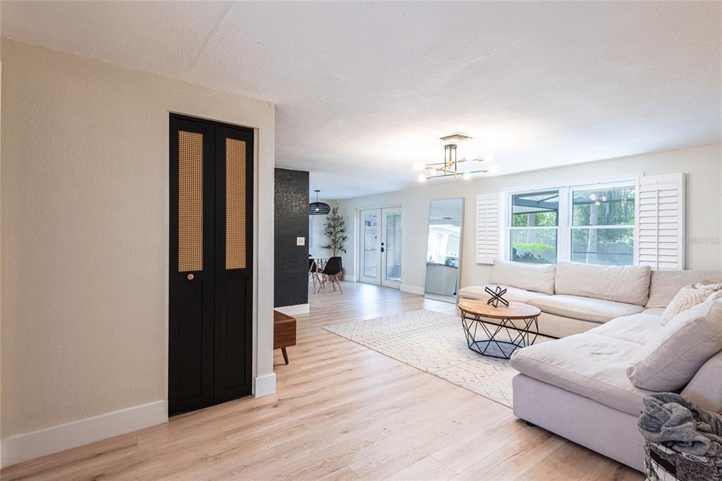 A living room features light wood flooring, a white sectional sofa, and a black closet — 2712 CEDARIDGE DRIVE, TAMPA, FL