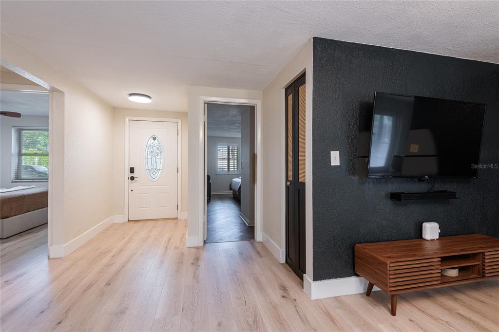 A hallway with light wood flooring leads to an entryway and a bedroom doorway — 2712 CEDARIDGE DRIVE, TAMPA, FL