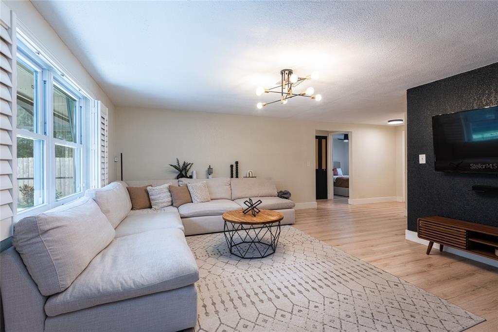 A living room features a light-colored sectional sofa, a round coffee table, and a television — 2712 CEDARIDGE DRIVE, TAMPA, FL