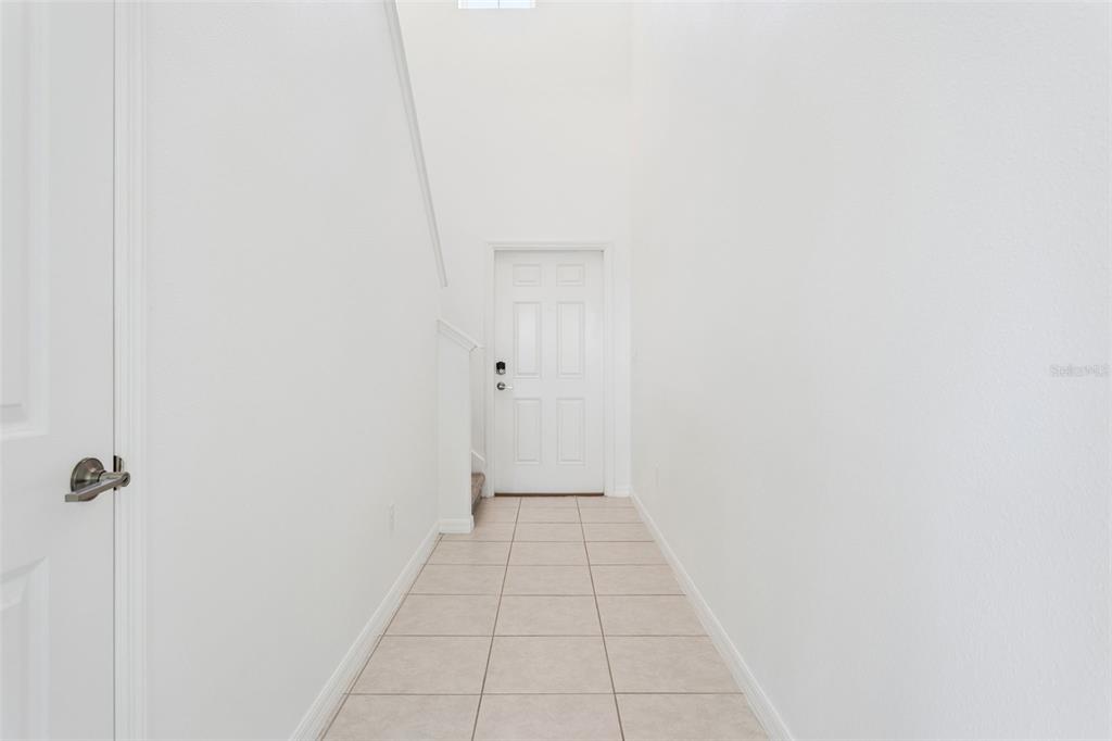 A bright, white-walled entryway features tiled flooring and a door at the end of the hall — 11000 RADIANT SHORE LOOP, SAN ANTONIO, FL