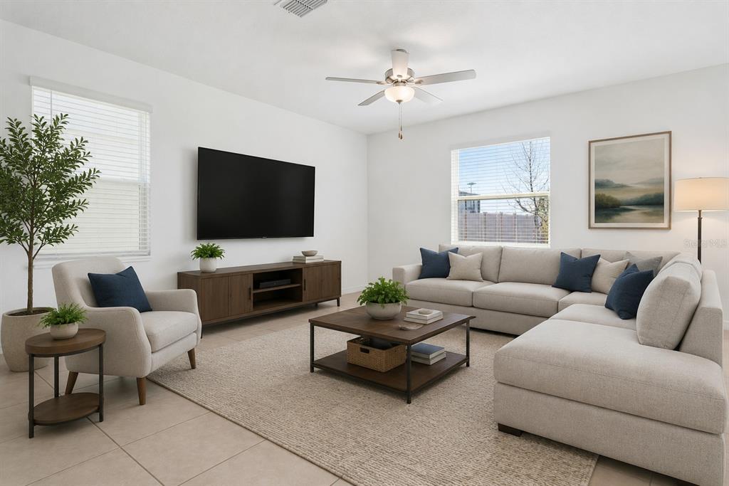 A living room features a sectional sofa, armchair, television, and coffee table on a rug — 11000 RADIANT SHORE LOOP, SAN ANTONIO, FL