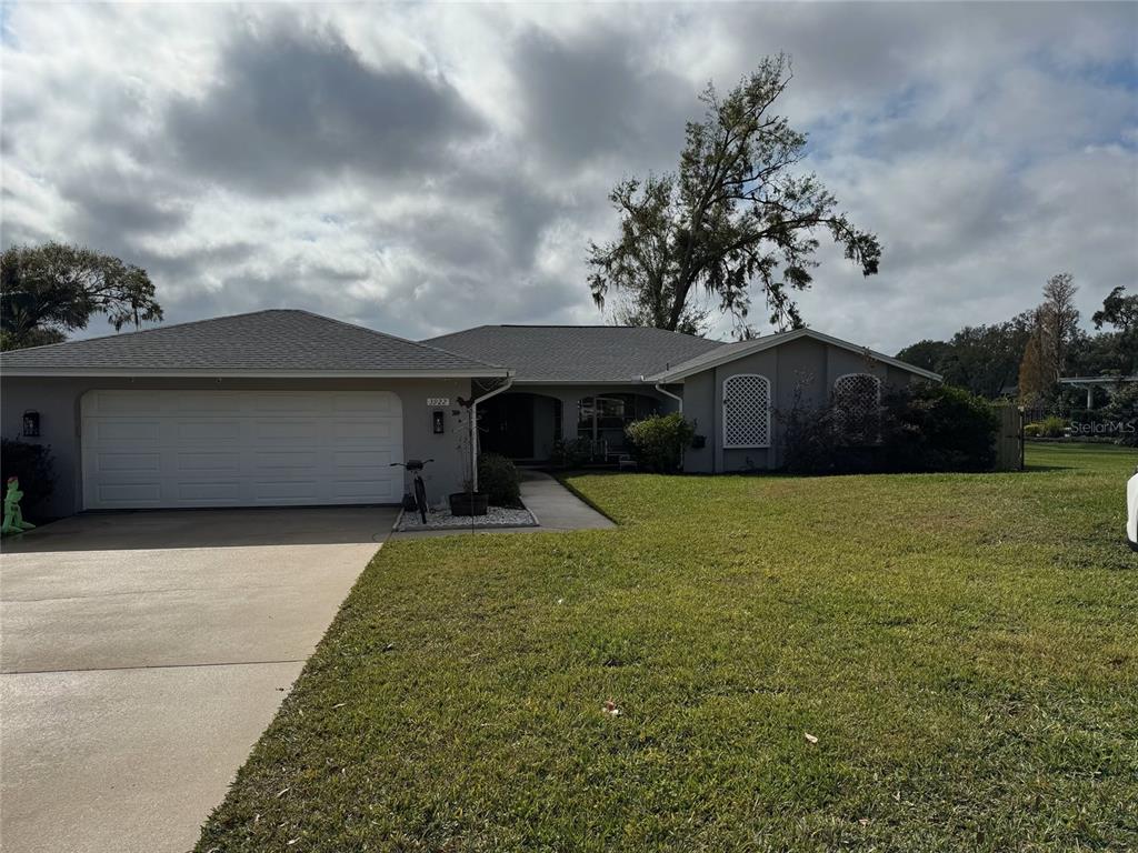 A single-story house with a two-car garage, gray exterior, and a large front lawn — 3922 LAKE JOYCE DRIVE, LAND O LAKES, FL