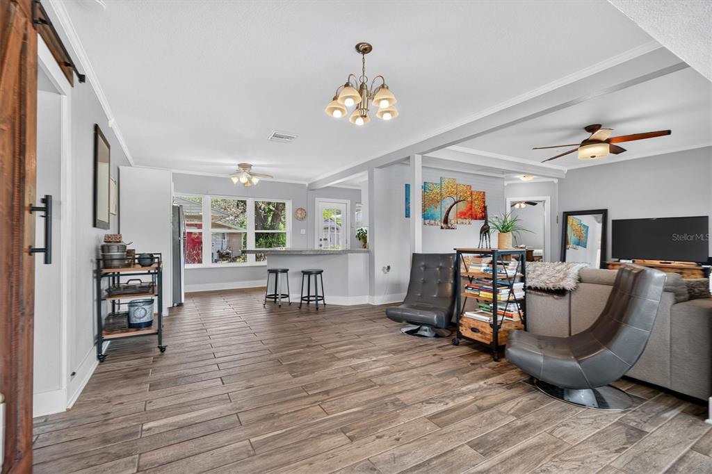 A living room and kitchen area feature wood-look tile flooring, gray walls, and a breakfast bar — 3701 VIRGINIA DRIVE, ORLANDO, FL