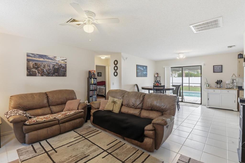 A living room with brown leather sofas, a ceiling fan, and tile flooring — 1393 HATHAWAY AVENUE, SPRING HILL, FL