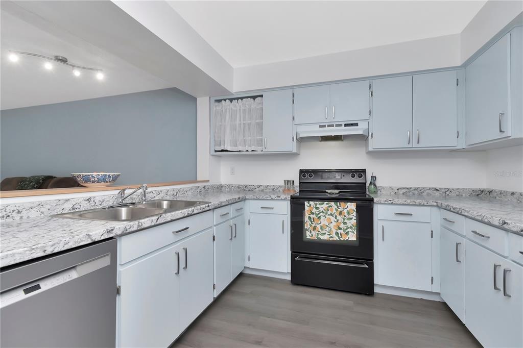 A kitchen with light blue cabinets, granite countertops, and black appliances — 6817 STONES THROW CIRCLE N UNIT 17203, ST PETERSBURG, FL