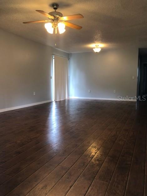 An empty room features dark wood-look flooring, a ceiling fan, and a sliding glass door — 810 E 20TH STREET, SANFORD, FL
