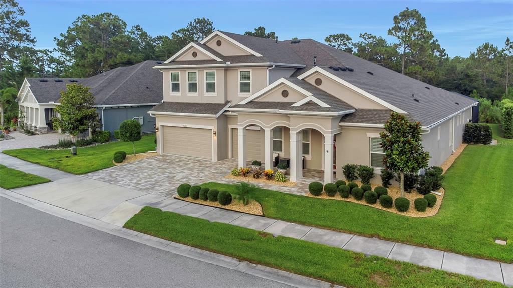 An aerial view of a two-story suburban house with a paved driveway and landscaped lawn — 4042 WOODLAND RETREAT BOULEVARD, NEW PORT RICHEY, FL