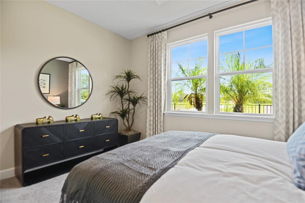 A bedroom features a dark dresser, a round mirror, a potted plant, and two windows — 32 PORTOFINO LANE, PALM COAST, FL
