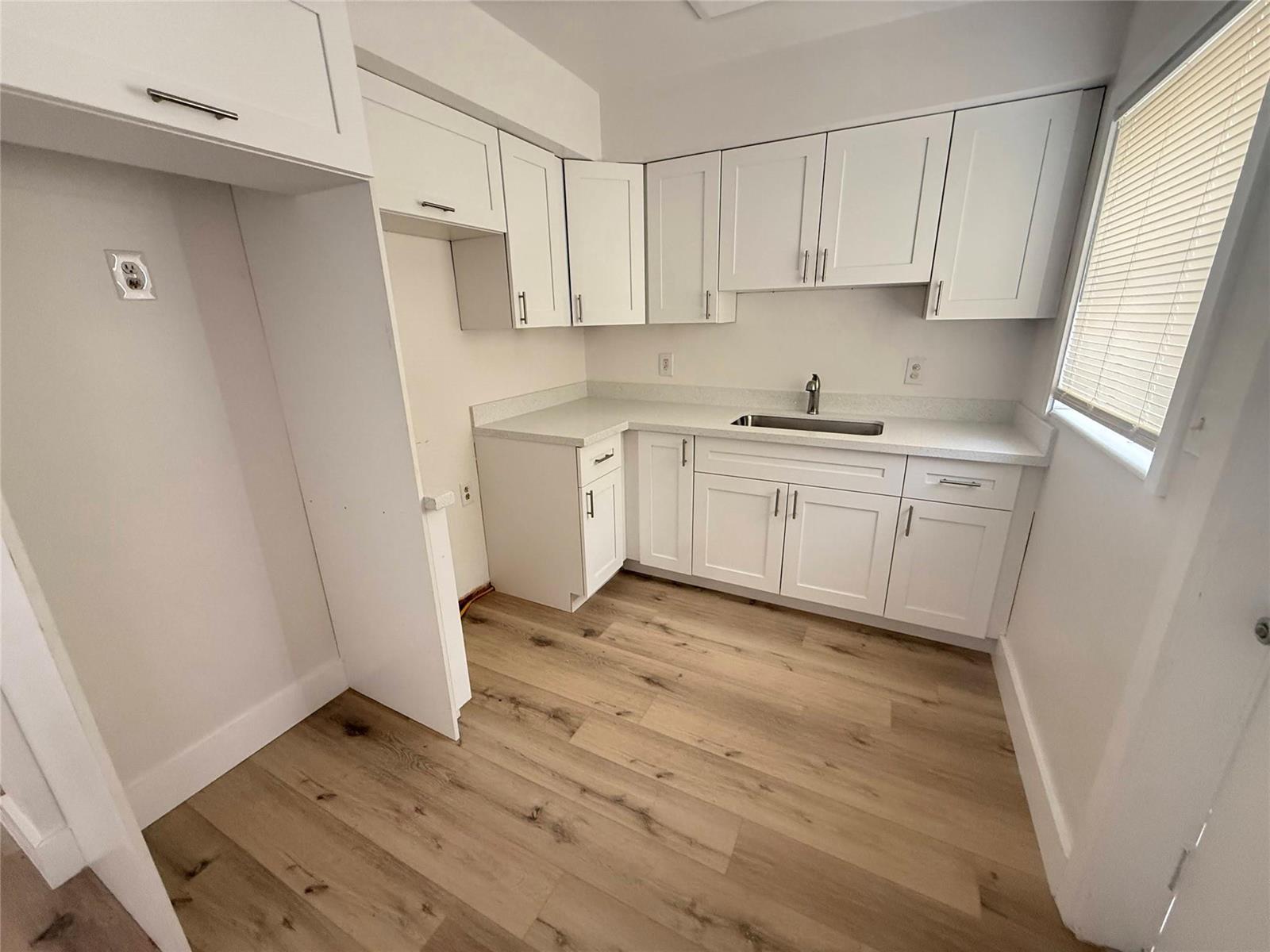 A kitchen features white cabinets, light countertops, and wood-look flooring — 811 E Broward Boulevard, Fort Lauderdale FL 33301, FORT LAUDERDALE, FL