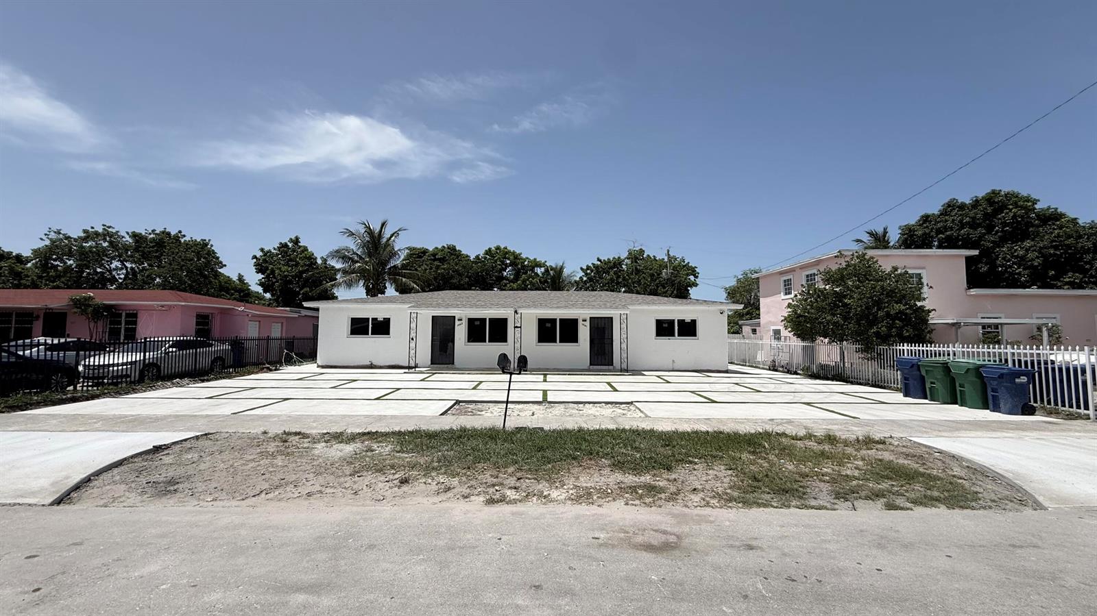 A white single-story duplex features a large concrete driveway with artificial turf grid accents — 1063 NW 108th Terrace, Miami FL 33168, MIAMI, FL