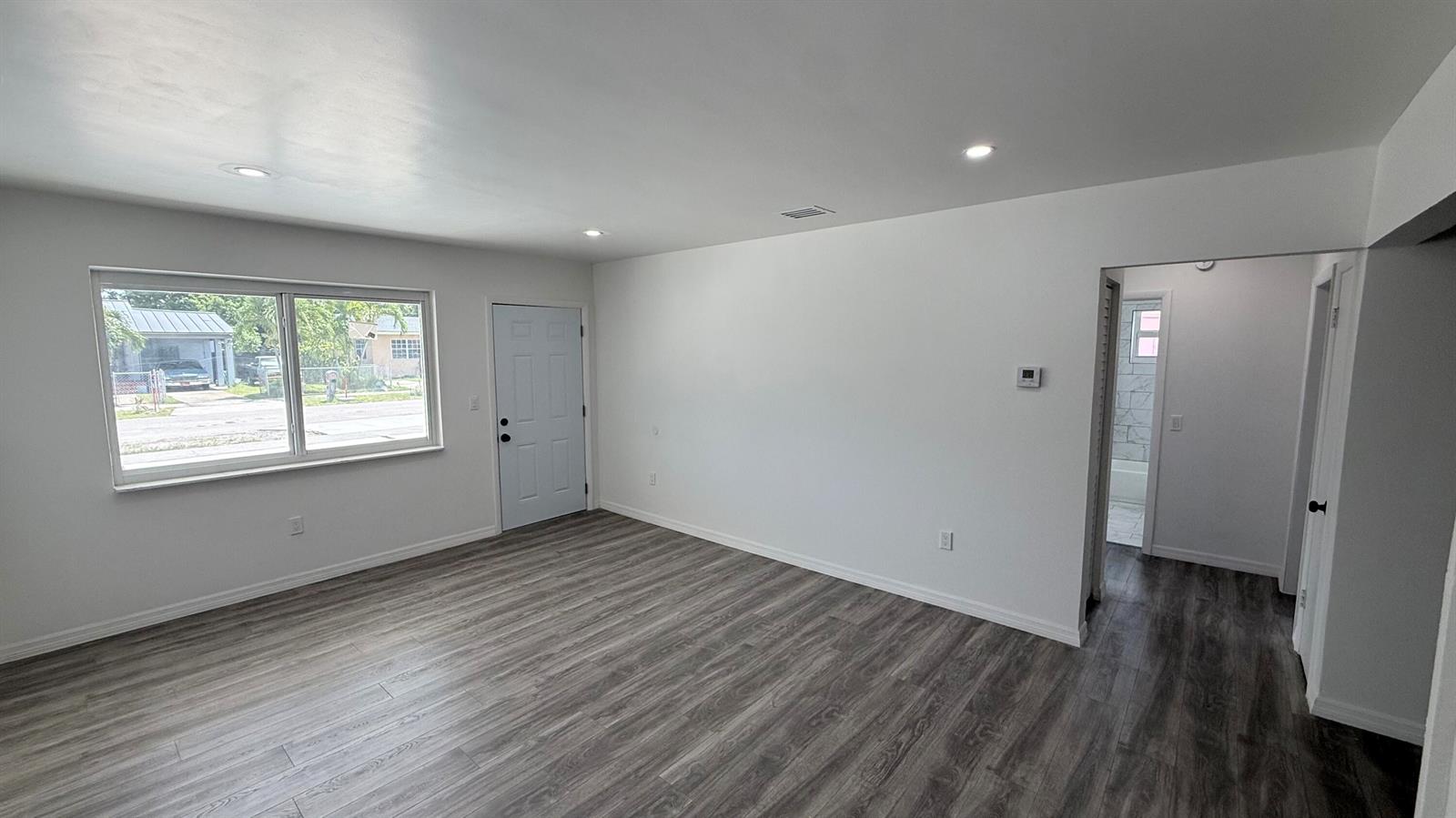An empty room features white walls, recessed lighting, and gray wood-look flooring — 1063 NW 108th Terrace, Miami FL 33168, MIAMI, FL