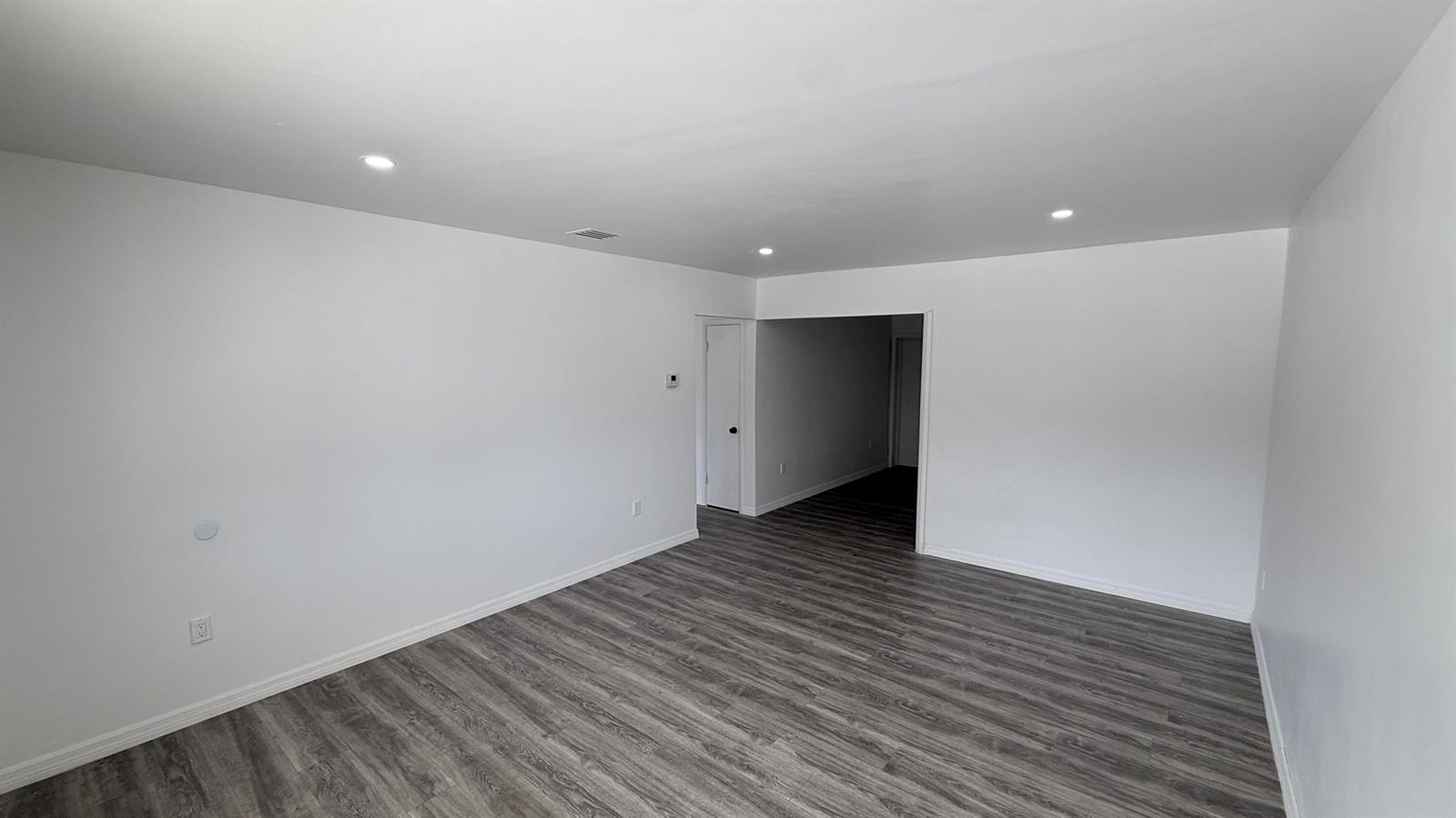 An empty room with white walls, recessed lighting, and gray wood-look plank flooring — 1063 NW 108th Terrace, Miami FL 33168, MIAMI, FL