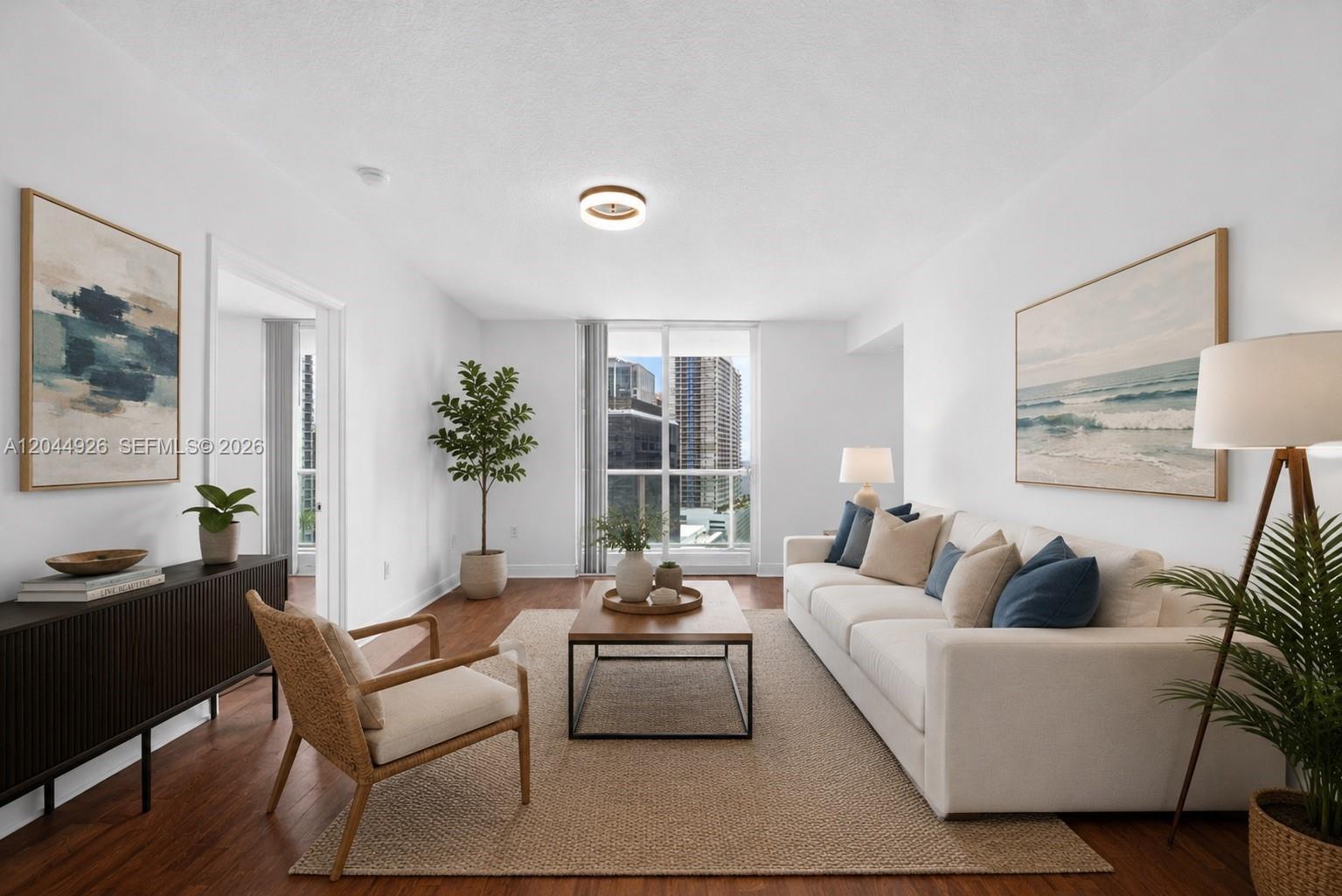 A bright living room features a white sofa, wooden coffee table, and large window views — 1250 S Miami Ave # 2004, Miami FL 33130, MIAMI, FL