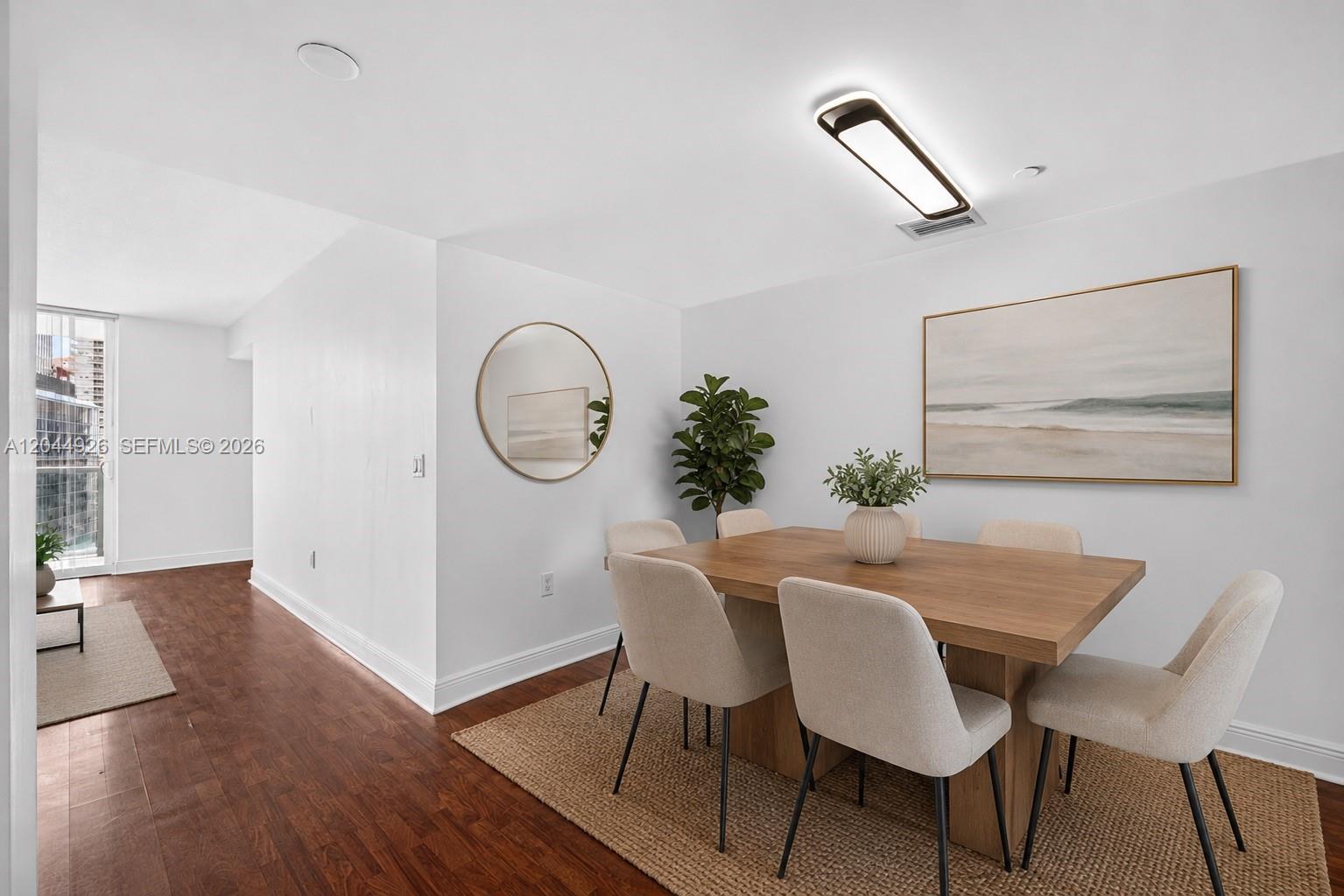 A dining room features a wooden table, light-colored chairs, a round mirror, and wall art — 1250 S Miami Ave # 2004, Miami FL 33130, MIAMI, FL