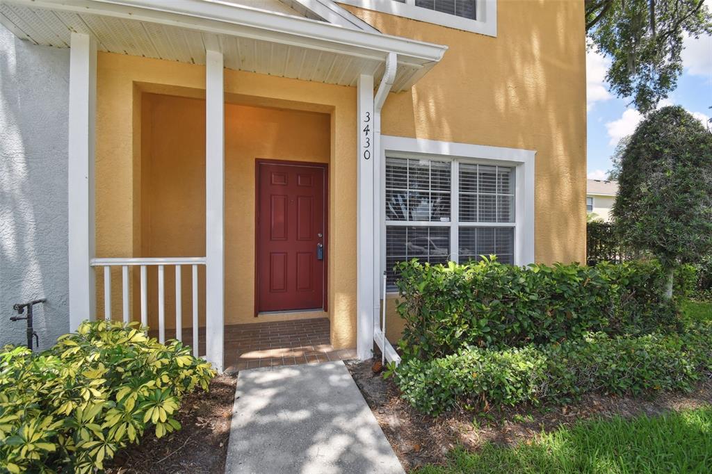 A yellow two-story house exterior features a red front door and a small covered porch — 3430 HIGH HAMPTON CIRCLE, TAMPA, FL