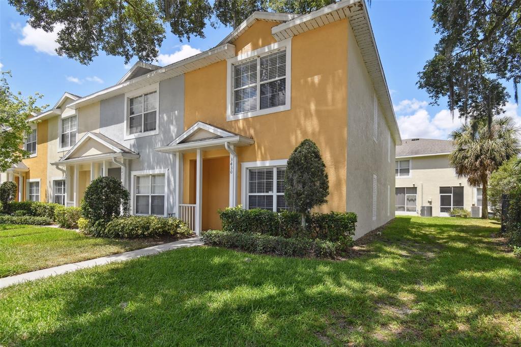 A two-story yellow townhouse with a small front porch and a grassy lawn — 3430 HIGH HAMPTON CIRCLE, TAMPA, FL