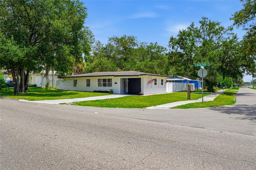 A white single-story house with a flat roof sits on a corner lot — 4015 RIVER HILLS DRIVE, TAMPA, FL