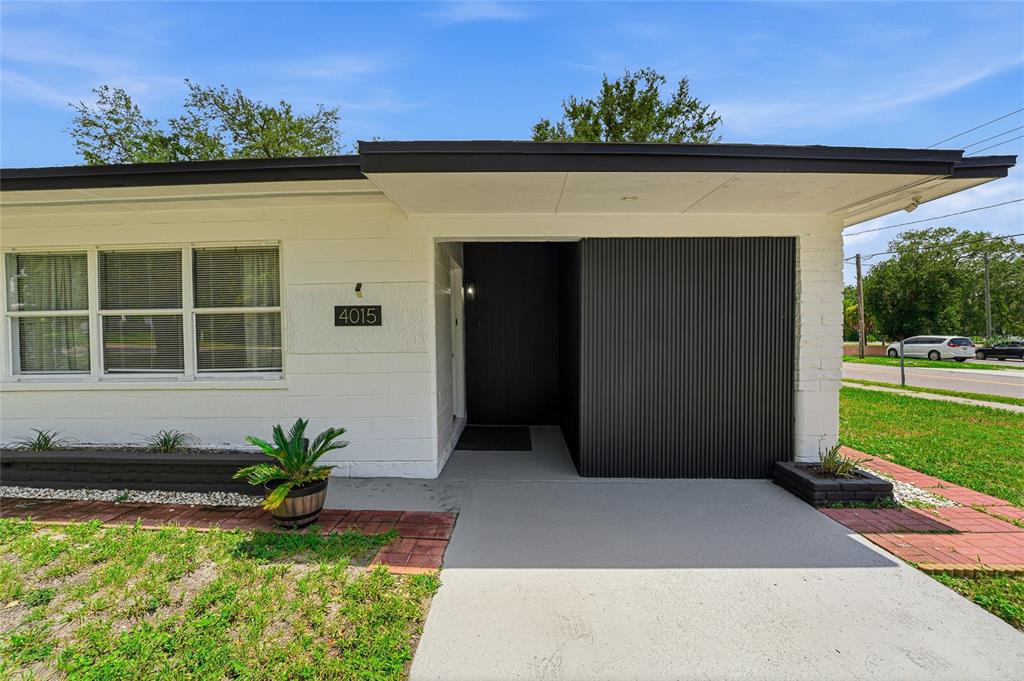 The exterior of a white house features a black front door and a corrugated wall — 4015 RIVER HILLS DRIVE, TAMPA, FL