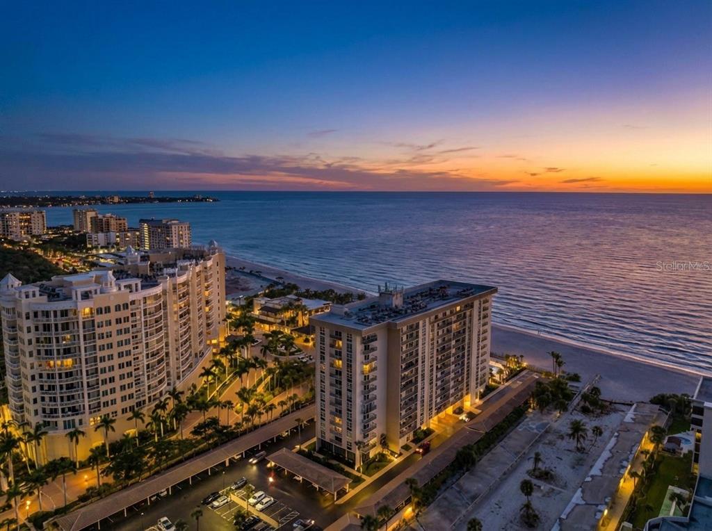 An aerial view of beachfront high-rise condominiums at sunset along a coastline — 1212 BENJAMIN FRANKLIN DRIVE UNIT 206, SARASOTA, FL