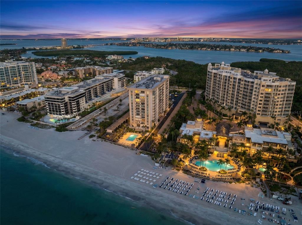 An aerial view of beachfront high-rise condominiums and resorts at dusk along a sandy coastline — 1212 BENJAMIN FRANKLIN DRIVE UNIT 206, SARASOTA, FL