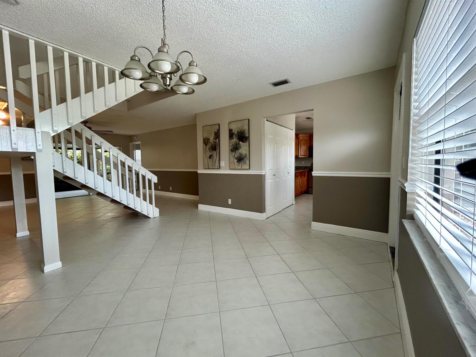 A tiled entryway features a white staircase, a chandelier, and two-toned wall paint — 16415 Berry Way, Delray Beach FL 33484, DELRAY BEACH, FL
