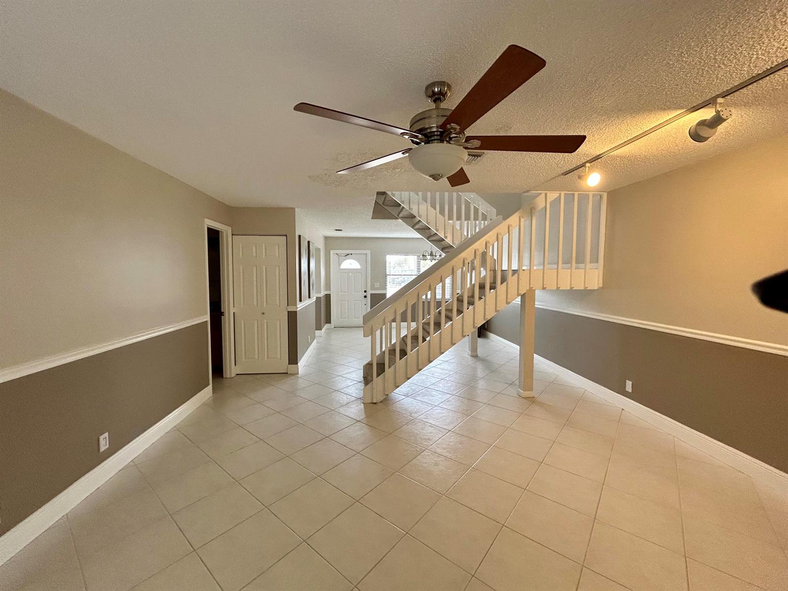 An open living area features tiled floors, a two-tone wall design, and a central staircase — 16415 Berry Way, Delray Beach FL 33484, DELRAY BEACH, FL