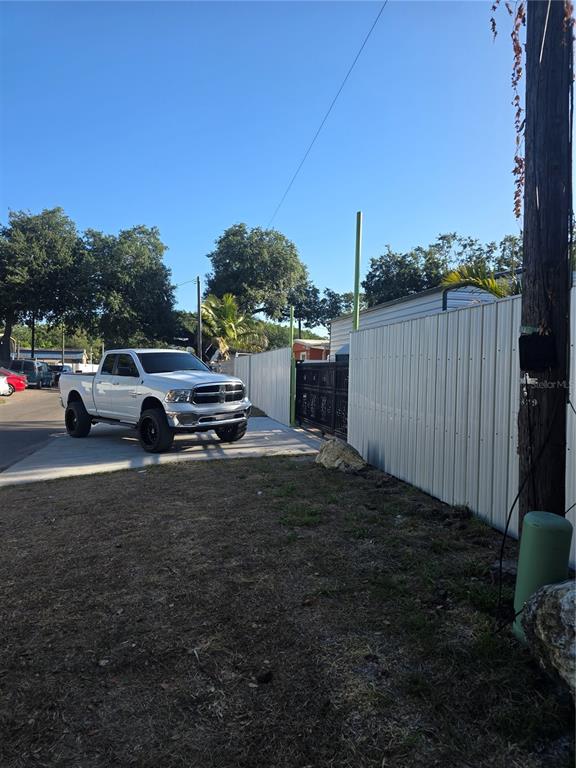 A white pickup truck is parked on a concrete driveway next to a metal fence — 5823 BARRY LANE, TAMPA, FL