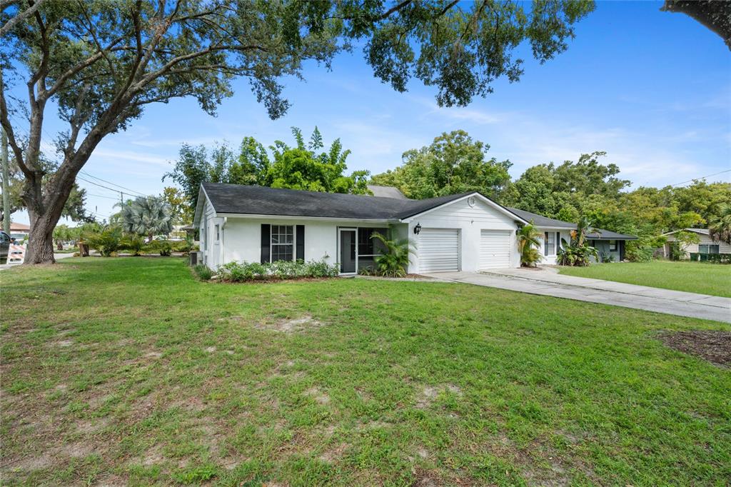 A single-story white house with two garage doors and a large front lawn — 125 N RHODES STREET, MOUNT DORA, FL
