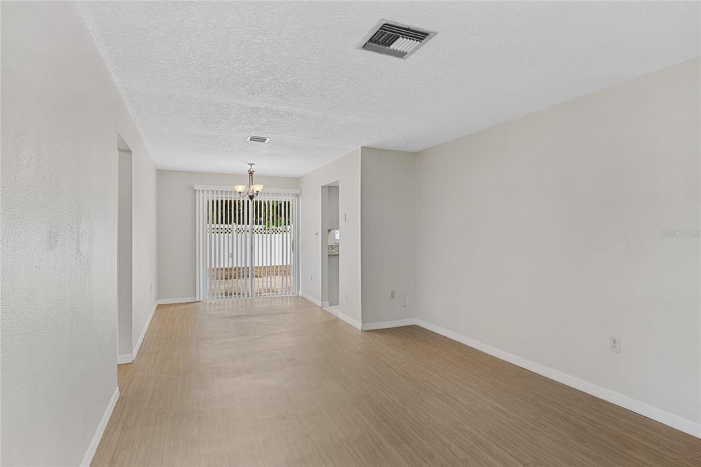 An empty room with light wood-look flooring, white walls, and sliding glass patio doors — 125 N RHODES STREET, MOUNT DORA, FL