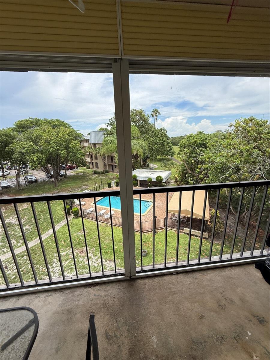 A view from a balcony overlooking a swimming pool, lawn, and surrounding apartment buildings — 5961 N Falls Cir Dr # 408, Lauderhill FL 33319, LAUDERHILL, FL