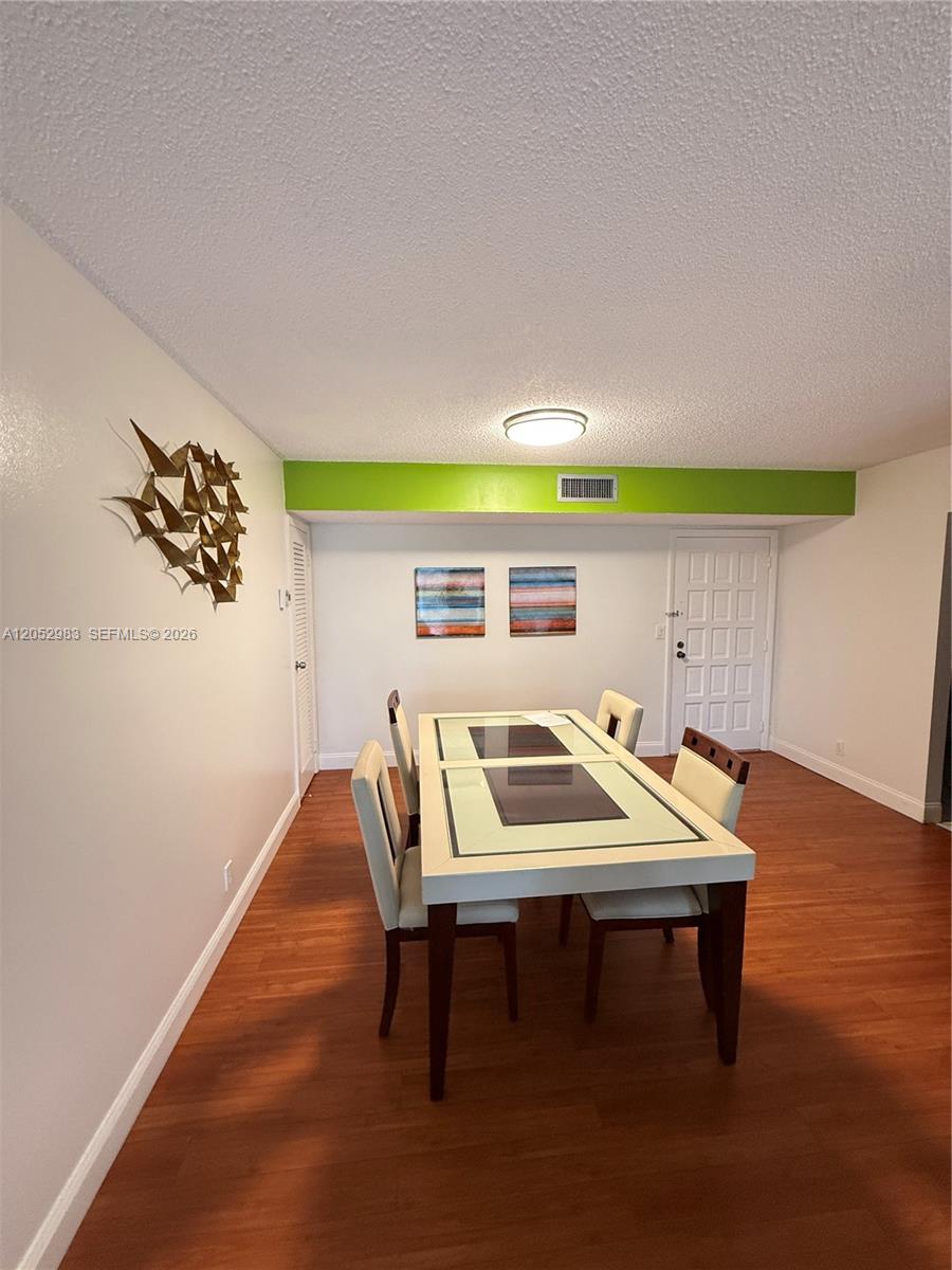 A dining room features a white table with four chairs, wood flooring, and wall art — 5961 N Falls Cir Dr # 408, Lauderhill FL 33319, LAUDERHILL, FL