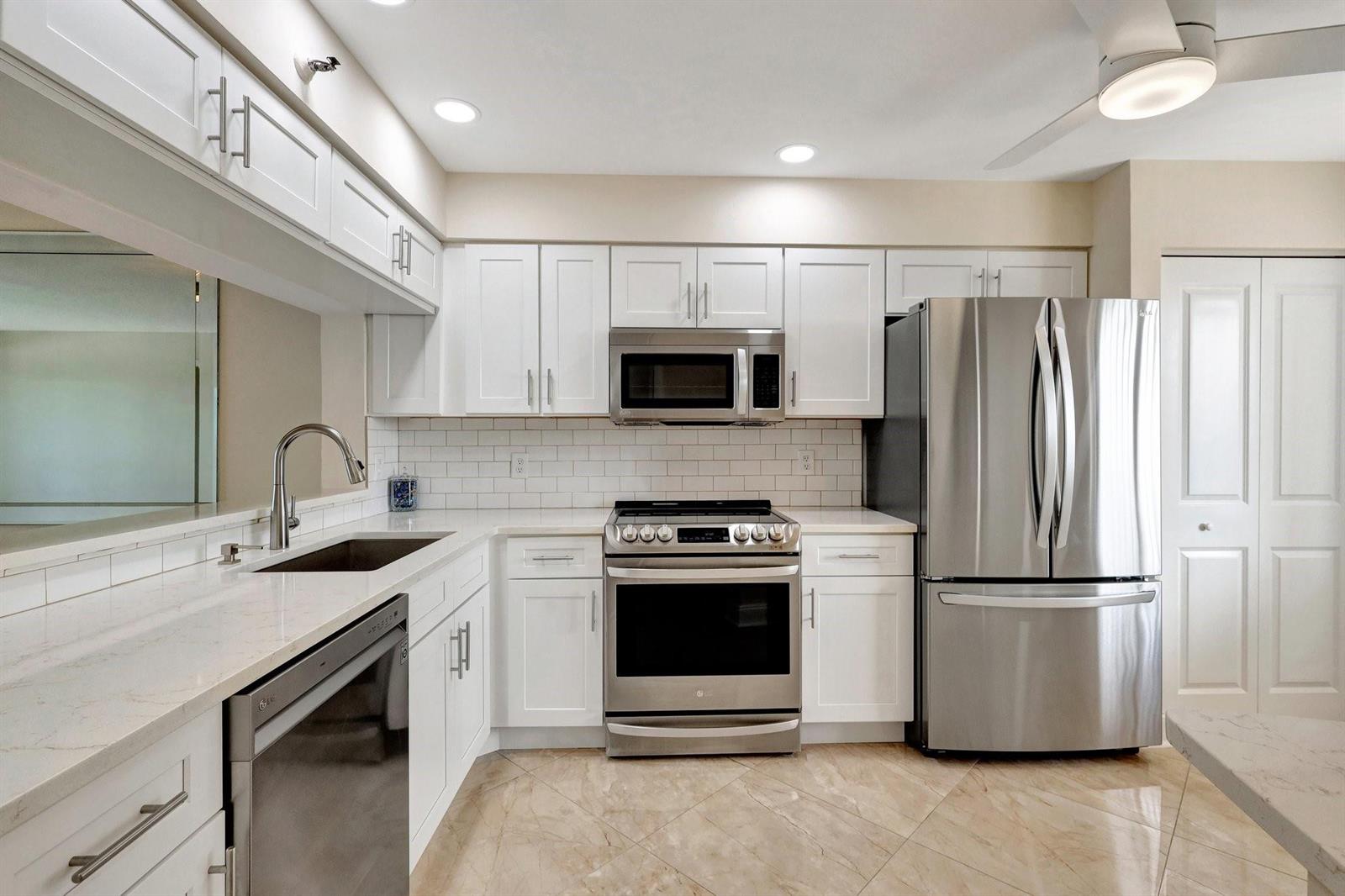 A kitchen with white cabinets, stainless steel appliances, white countertops, and a subway tile backsplash — 14460 Strathmore Lane # 807, Delray Beach FL 33446, DELRAY BEACH, FL