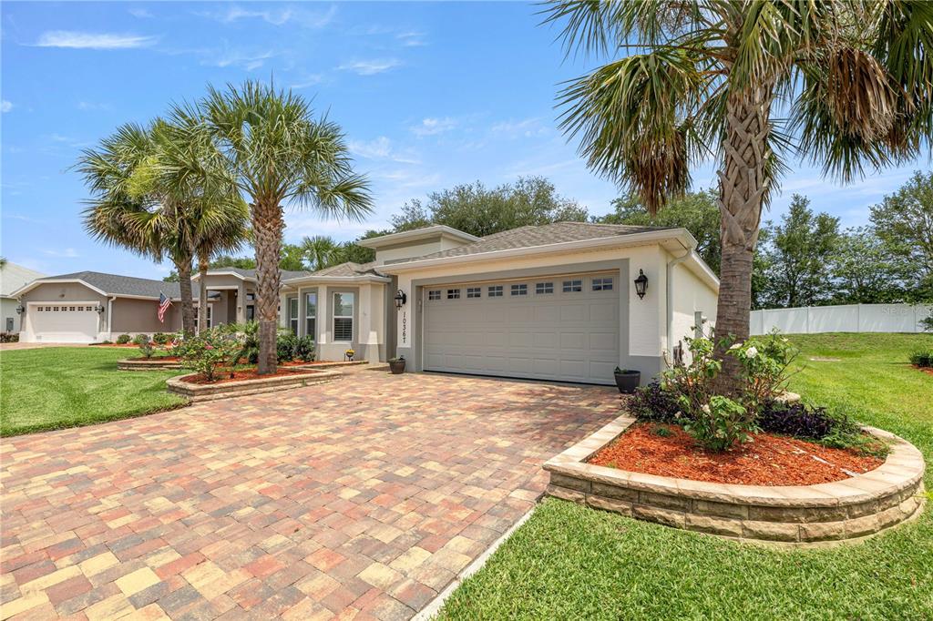 A single-story house with a paved driveway, a two-car garage, and palm trees in front — 10367 ADDISON SHORE WAY, OXFORD, FL