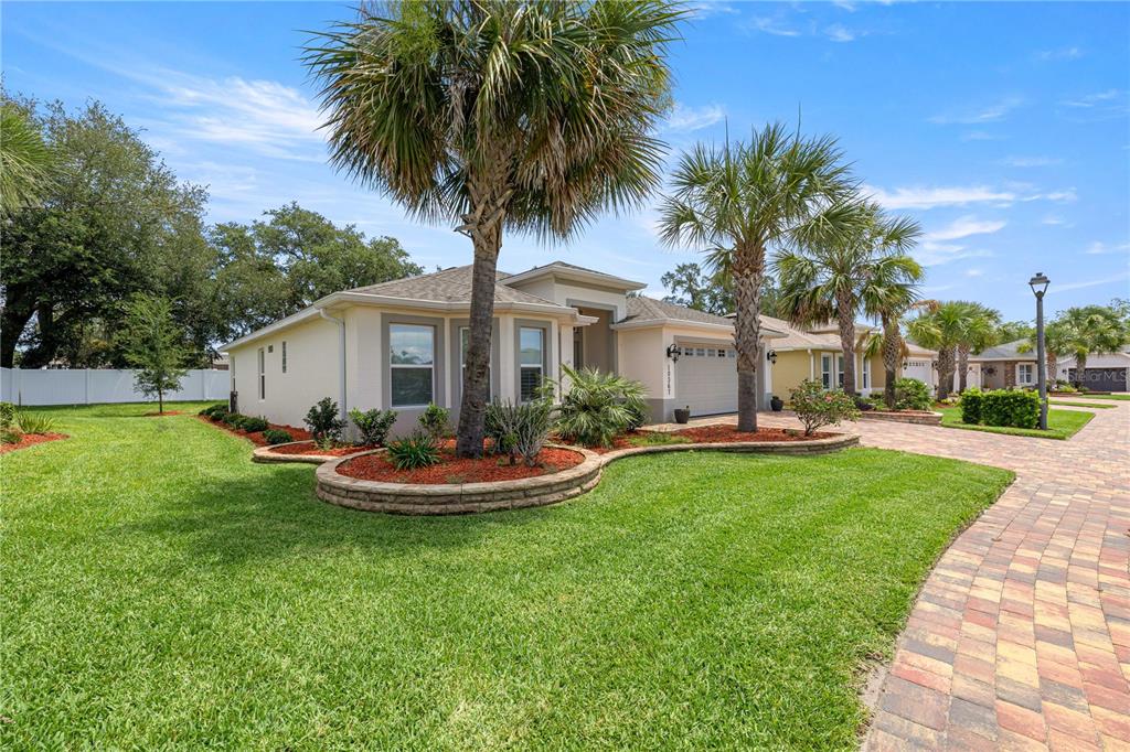 A single-story house with a paved driveway, palm trees, and a landscaped front yard — 10367 ADDISON SHORE WAY, OXFORD, FL