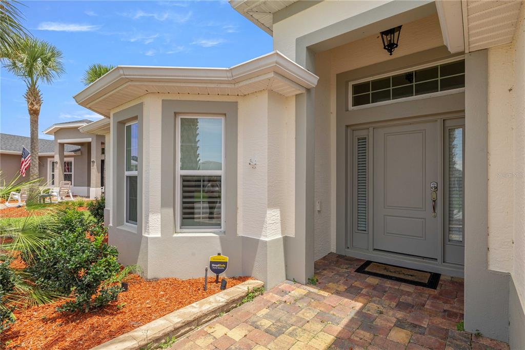 The exterior of a house features a paved walkway leading to a gray front door — 10367 ADDISON SHORE WAY, OXFORD, FL