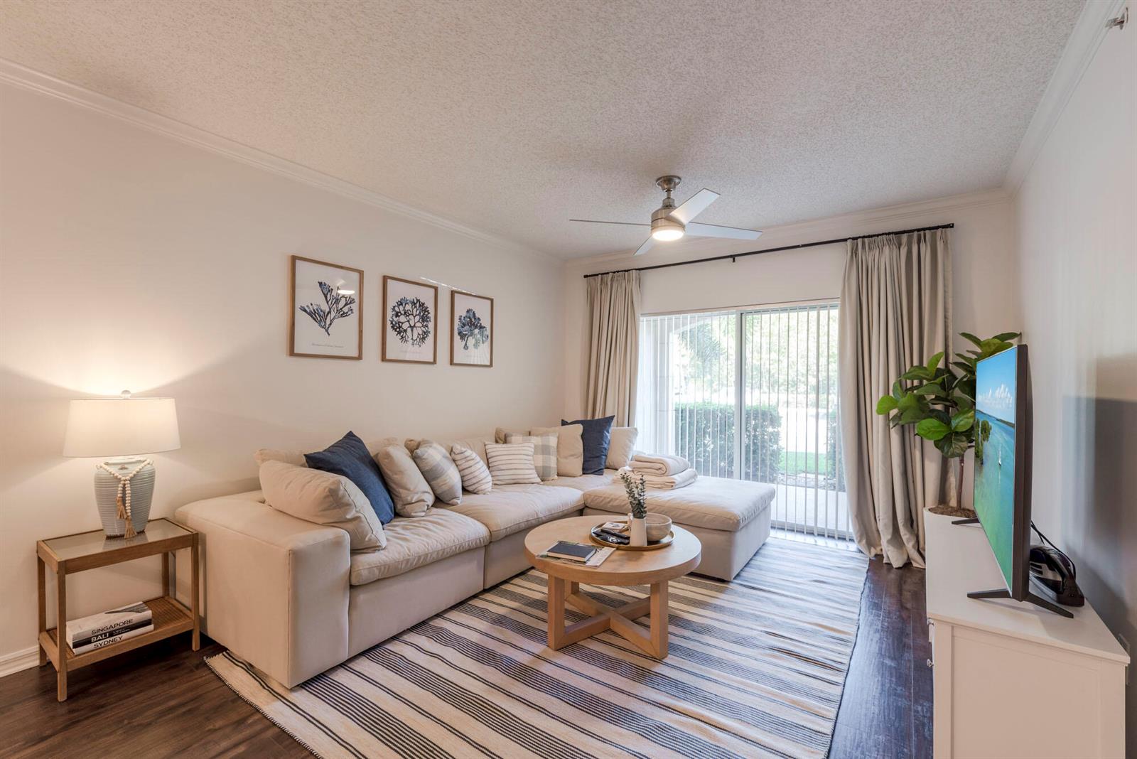 A living room features a beige sectional sofa, a round wooden coffee table, and a television — 3117 Tuscany Way, Boynton Beach FL 33435, BOYNTON BEACH, FL