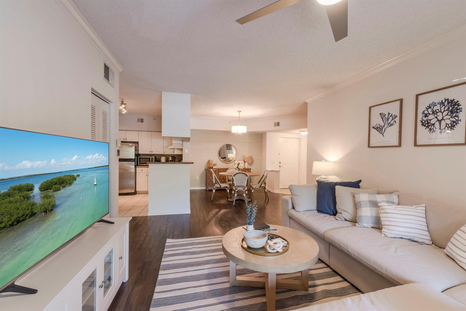 A living room with dark wood floors, a sectional sofa, and an open kitchen area — 3117 Tuscany Way, Boynton Beach FL 33435, BOYNTON BEACH, FL