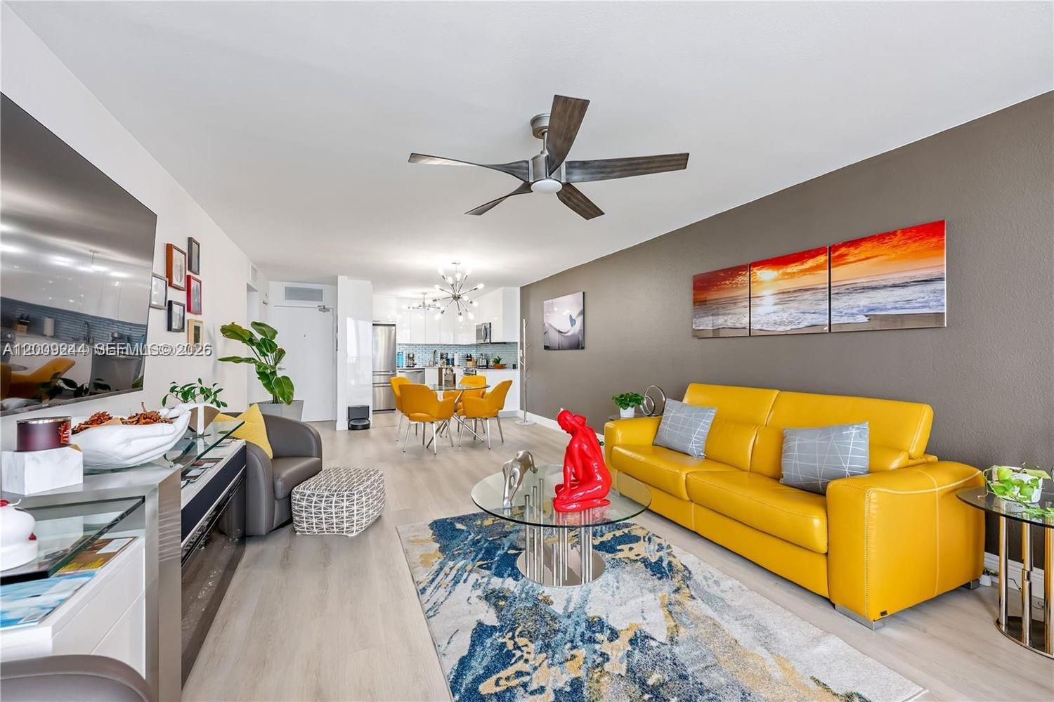 A living room features a bright yellow sofa, a glass coffee table, and light flooring — 2201 S Ocean Dr # 2202, Hollywood FL 33019, HOLLYWOOD, FL
