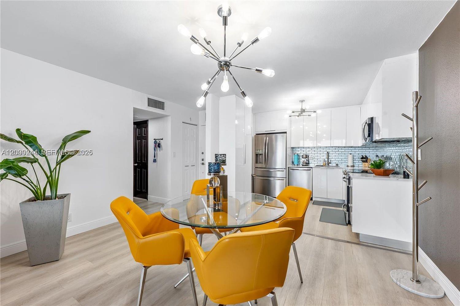 A dining area with a glass table and yellow chairs sits beside a modern kitchen — 2201 S Ocean Dr # 2202, Hollywood FL 33019, HOLLYWOOD, FL