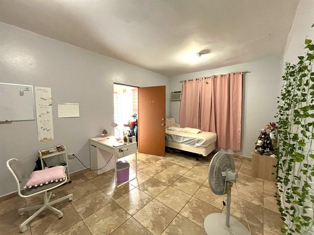 A bedroom with tiled floors, a single bed, a desk, and a wall of hanging vines — 62 CALLE BOGOTÁ, MAYAGUEZ, PR