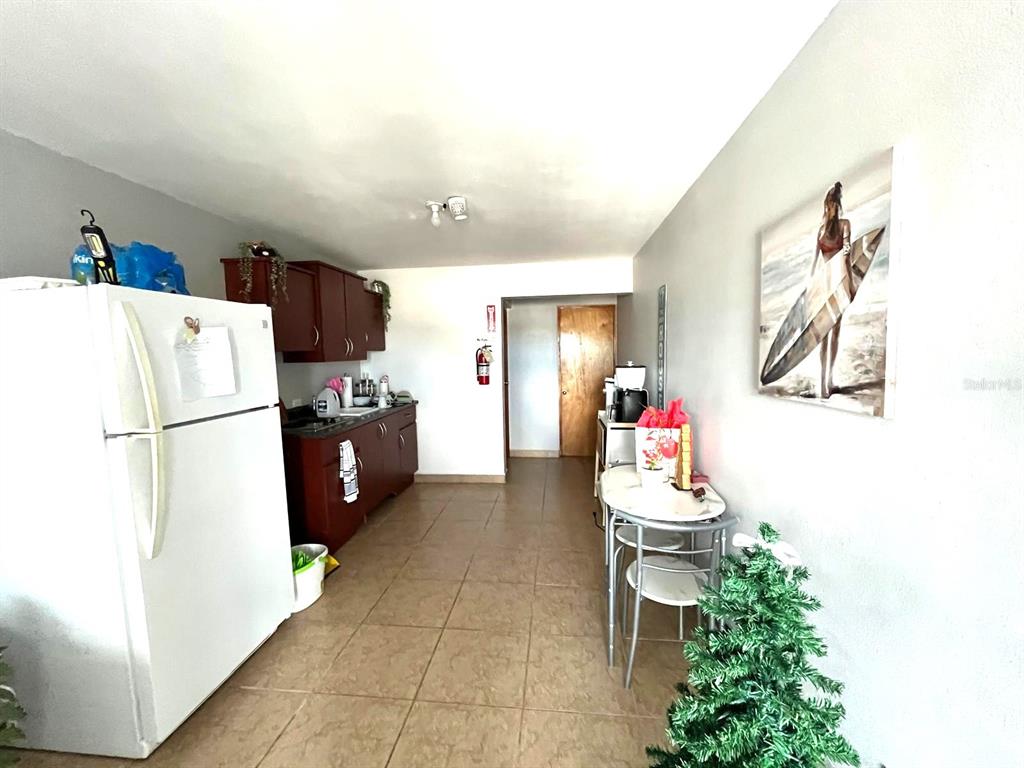 A kitchen with dark wood cabinets, a white refrigerator, and a small dining table — 62 CALLE BOGOTÁ, MAYAGUEZ, PR